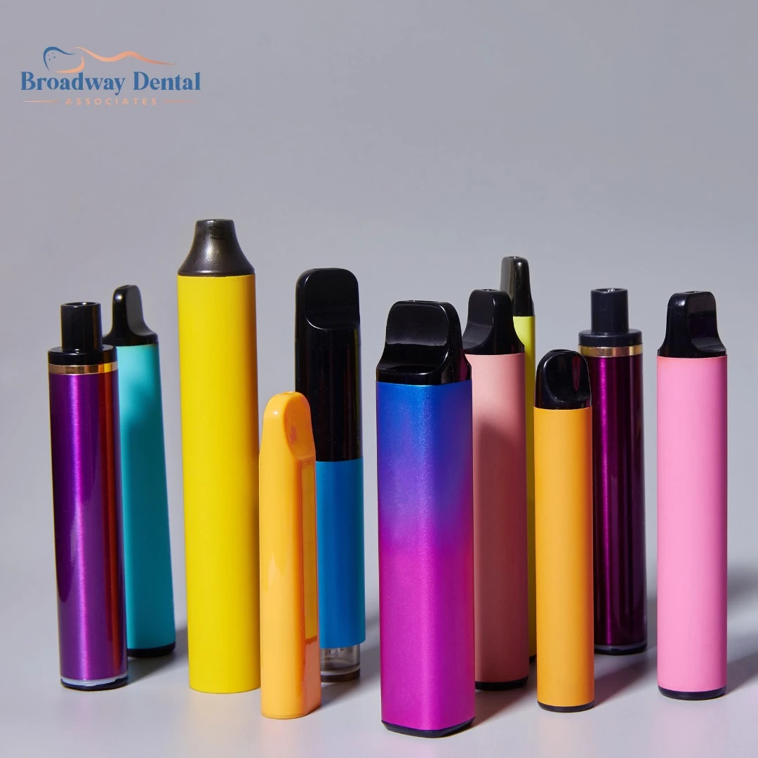 A variety of colorful vapes are standing upright on a grey surface