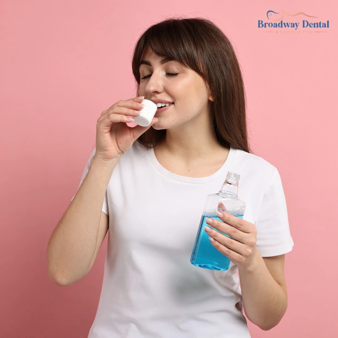 A young woman using a bottle of blue mouthwash, highlighting proper dental hygiene to avoid bad breath
