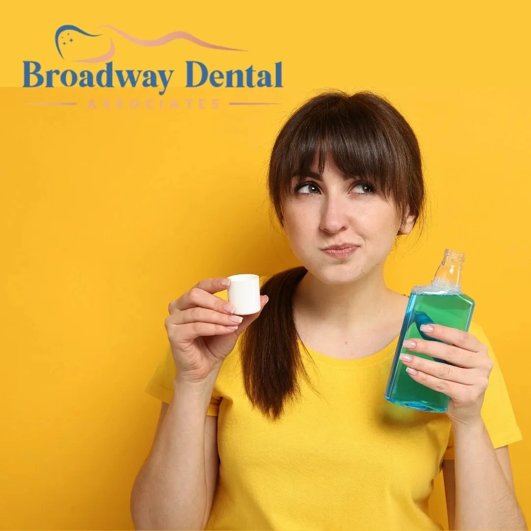 A woman holding mouthwash, rinsing her mouth, wearing a yellow shirt with a yellow background