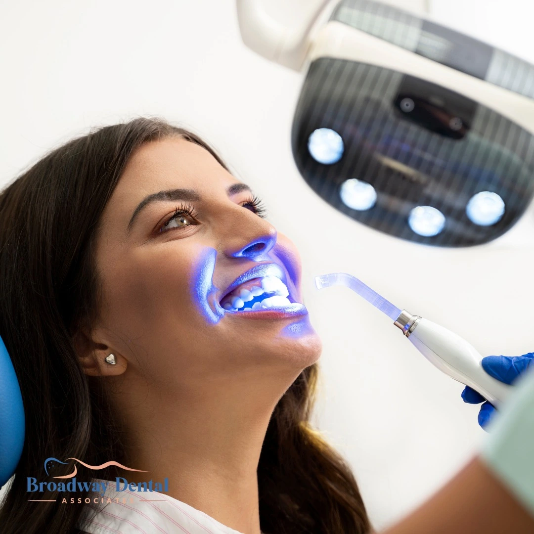 woman receiving professional laser teeth whitening, and Broadway Dental Associates logo in the bottom left of the image