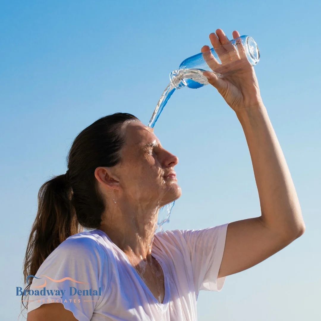 A woman pouring cold water over her face outdoors and Broadway Dental Associates logo in the bottom left of the image