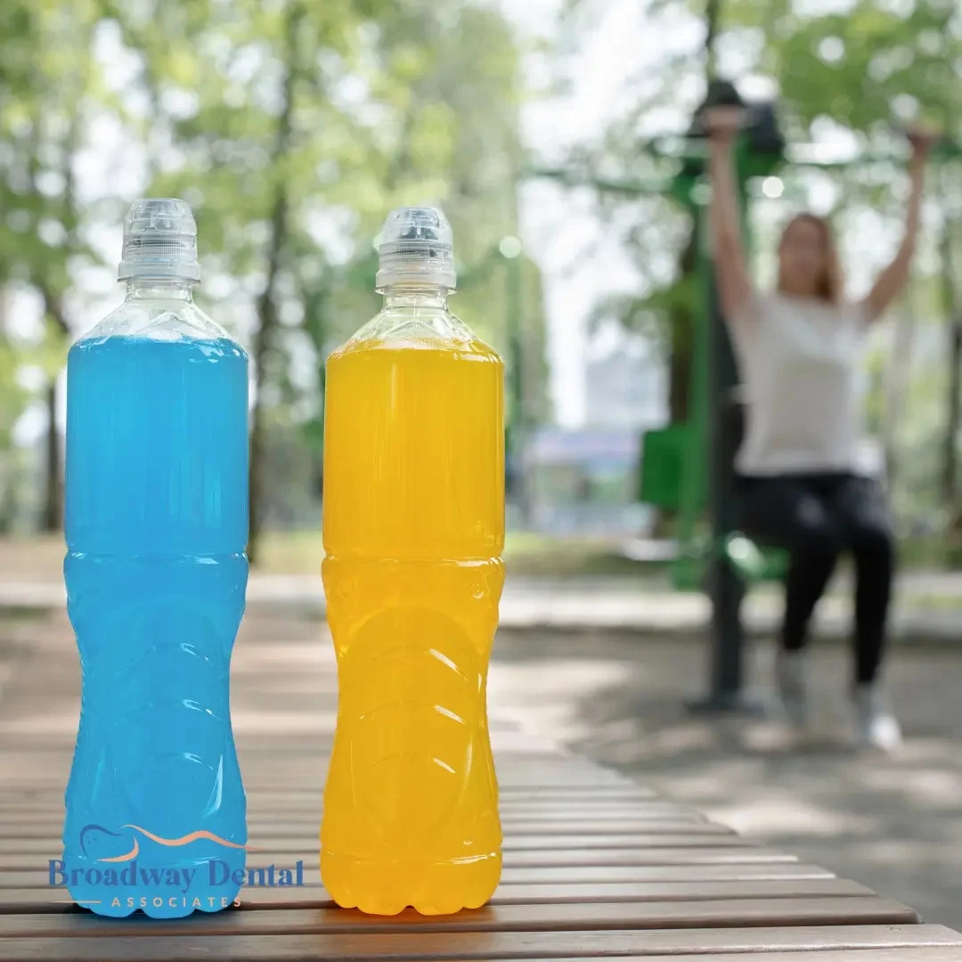 Two sports drink bottles on a park bench and Broadway Dental Associates logo in the bottom left of the image