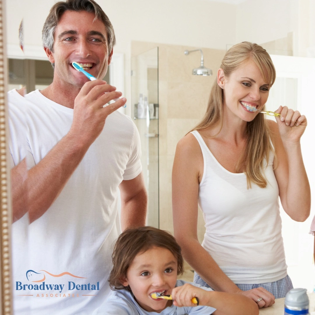 Family brushing teeth together in bathroom and Broadway Dental Associates logo in the bottom left of the image.