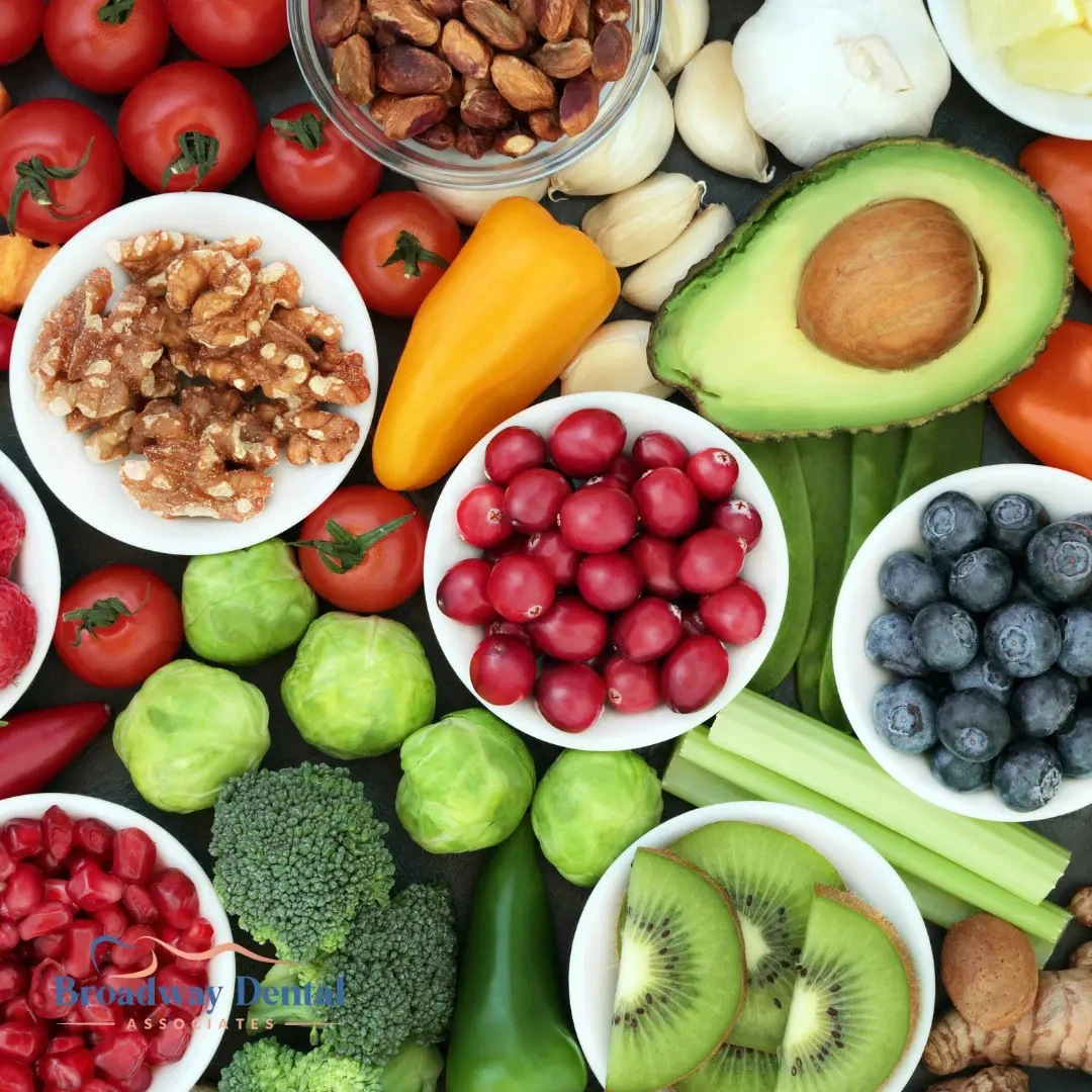 Variety of fresh fruits, vegetables, and nuts and Broadway Dental Associates logo in the bottom left of the image.
