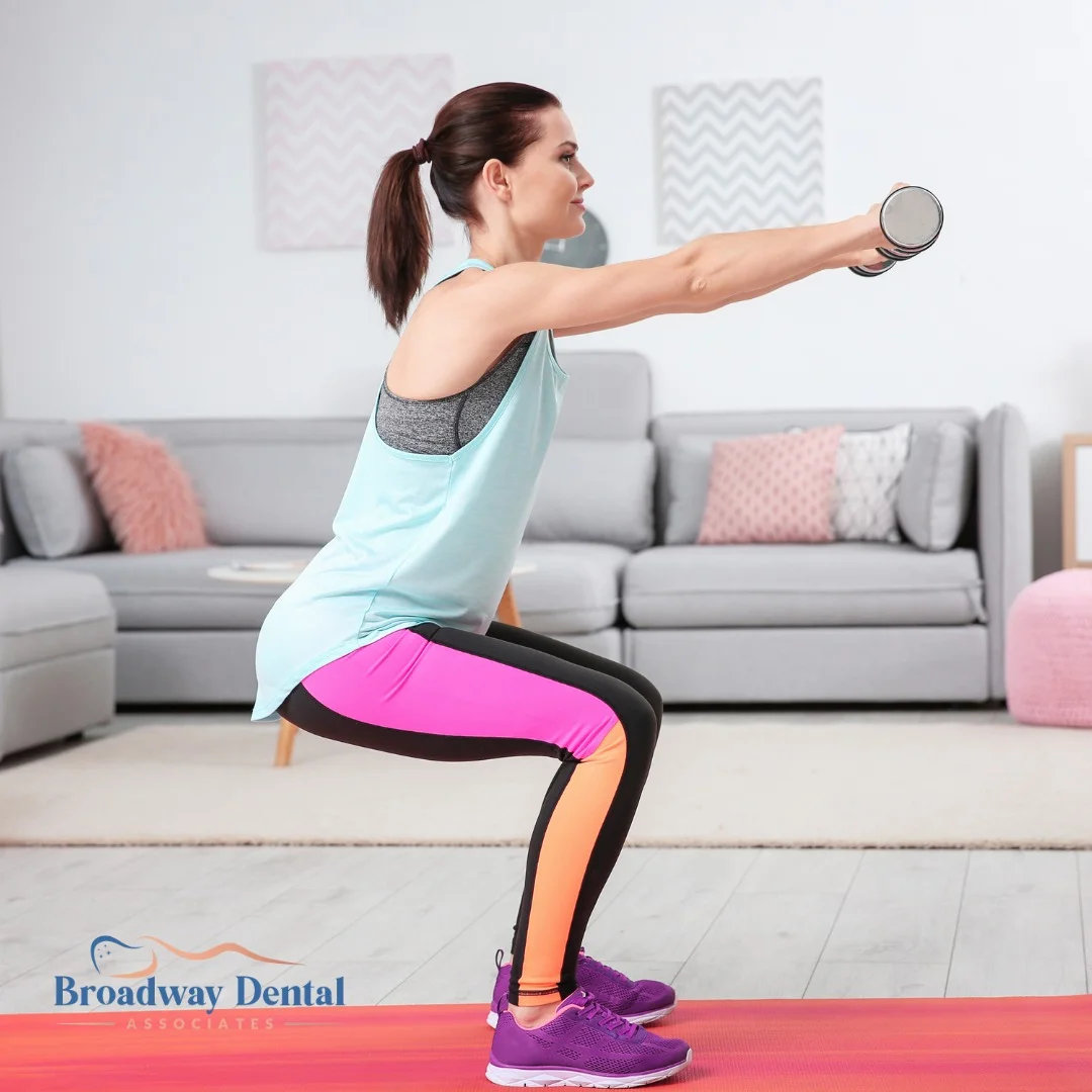 Woman doing squat exercises with dumbbells and Broadway Dental Associates logo in the bottom left of the image